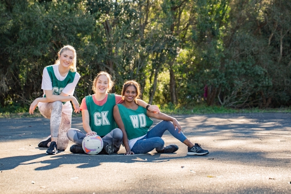 horizontal shot of three young smiling women in sports wear posing for a photo op on a sunny day - Australian Stock Image