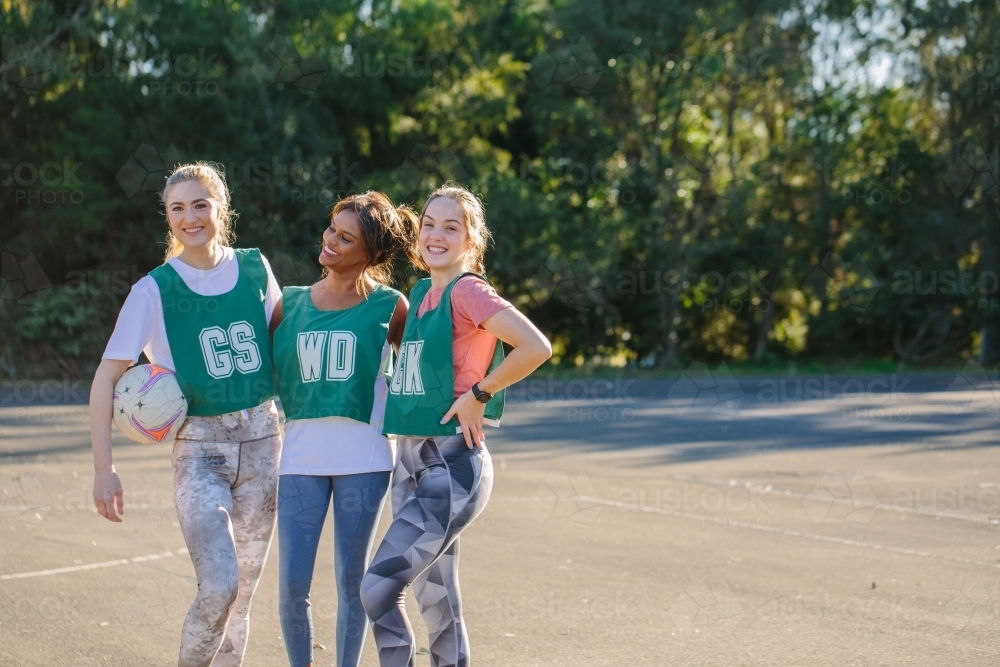 horizontal shot of three young women in sports wear posing outdoors on a sunny day - Australian Stock Image