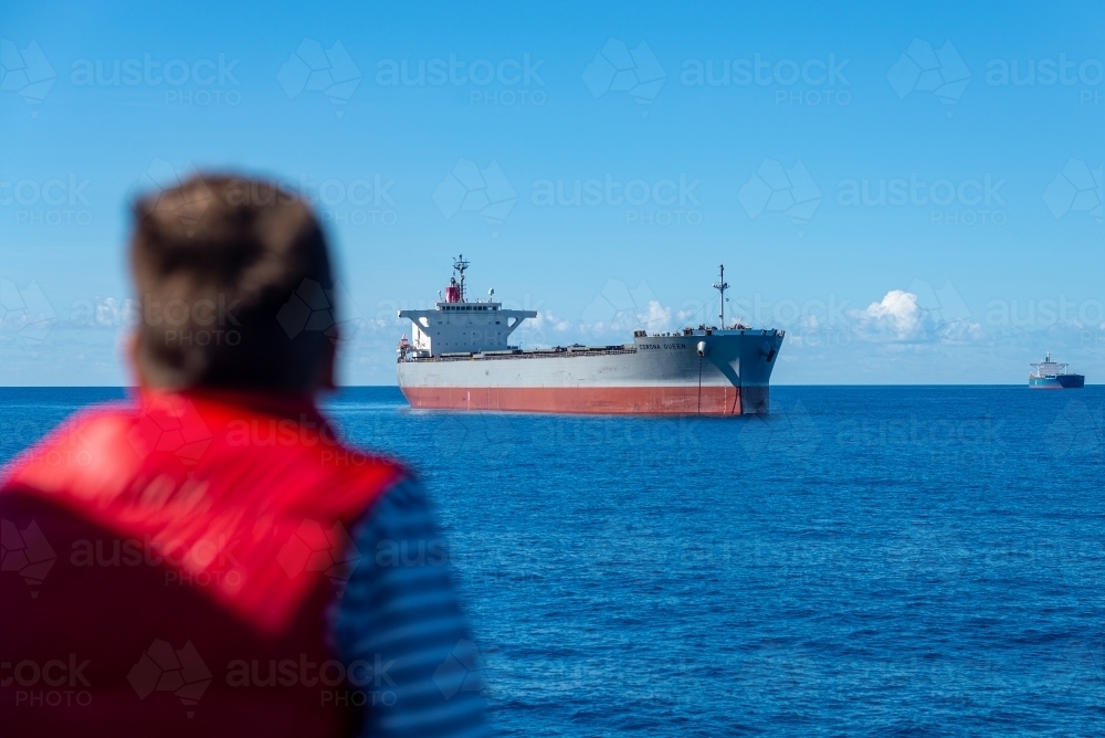 Horizontal shot of two cargo ships sailing with a person looking at them - Australian Stock Image