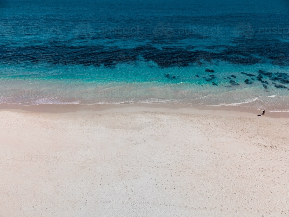horizontal shot of white sand beach with waves and seaweeds on a sunny day - Australian Stock Image