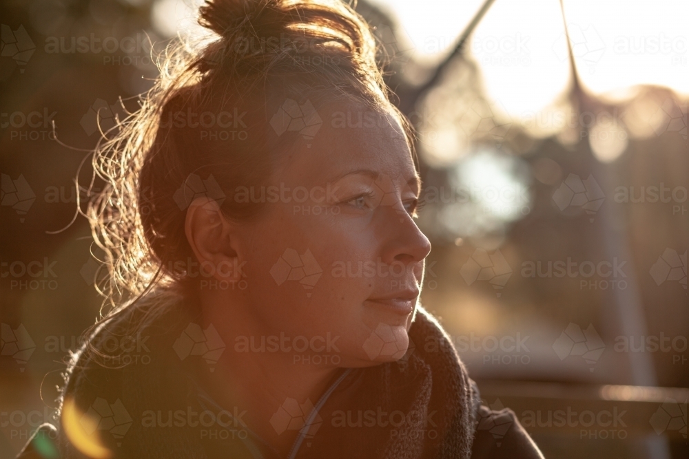 horizontal shot of woman with a messy bun hairstyle looking from a far on a sunny day - Australian Stock Image