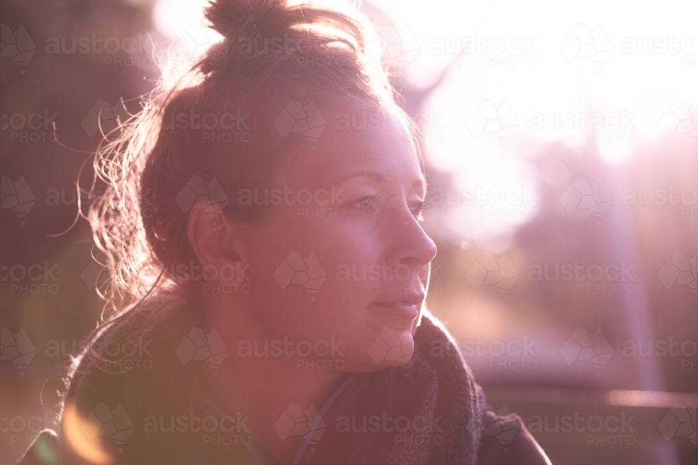 horizontal shot of woman with a messy bun hairstyle looking from a far on a sunny day - Australian Stock Image