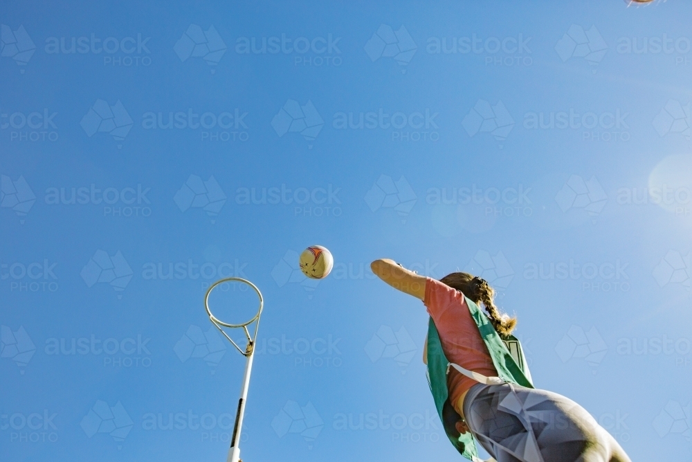 horizontal shot of young woman throwing net ball in mid air on a sunny day - Australian Stock Image