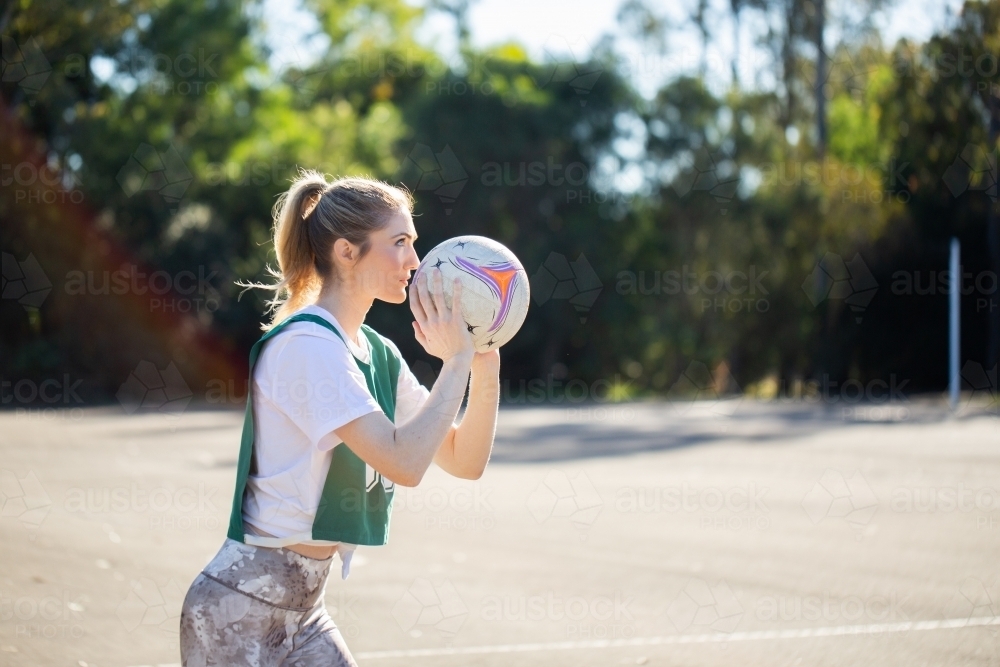 horizontal side view shot of woman in sports wear holding a net ball on a sunny day outdoors - Australian Stock Image