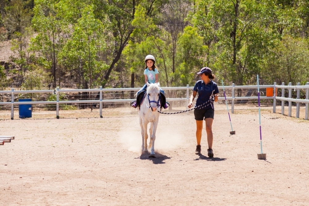 Image of Horse riding instructor leading student on horse for first ...