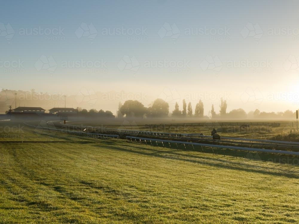 Horse training at a racecourse in early morning mist - Australian Stock Image
