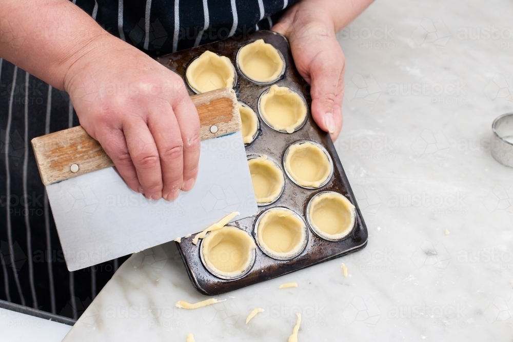 Hospitality worker cutting pastry from a tray - Australian Stock Image