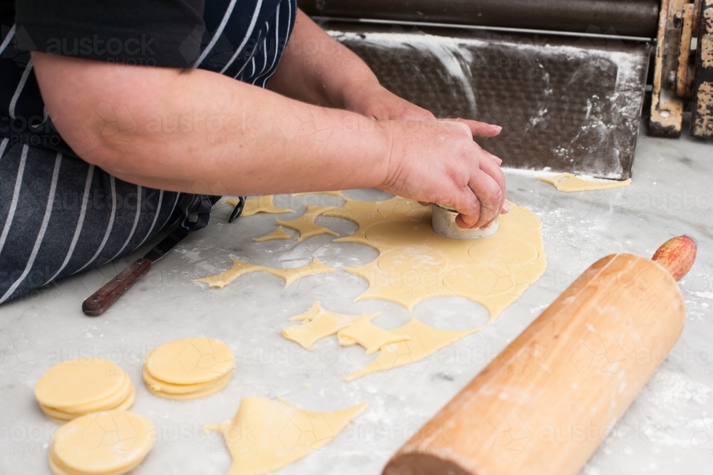 Hospitality worker cutting pastry in circles - Australian Stock Image