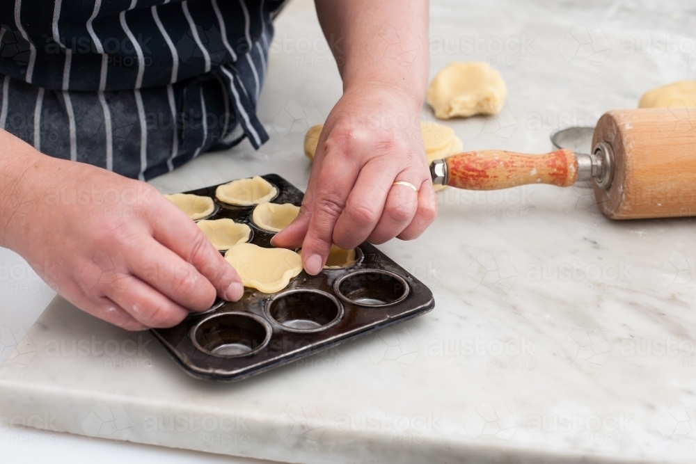 Hospitality worker forming pastry into a tray - Australian Stock Image