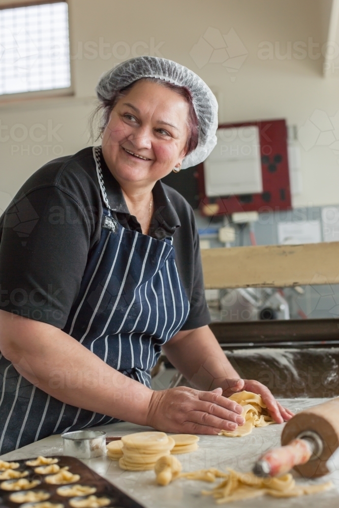 hospitality worker making pastry in a commercial kitchen - Australian Stock Image