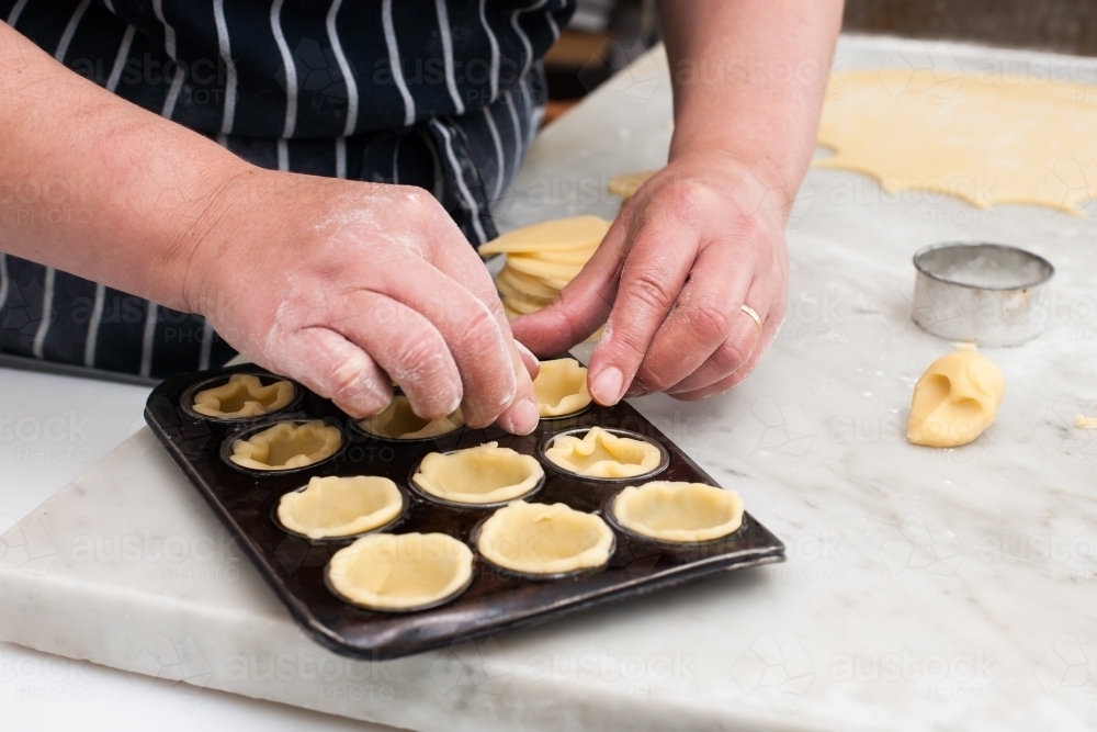 Hospitality worker making pastry into a tray - Australian Stock Image