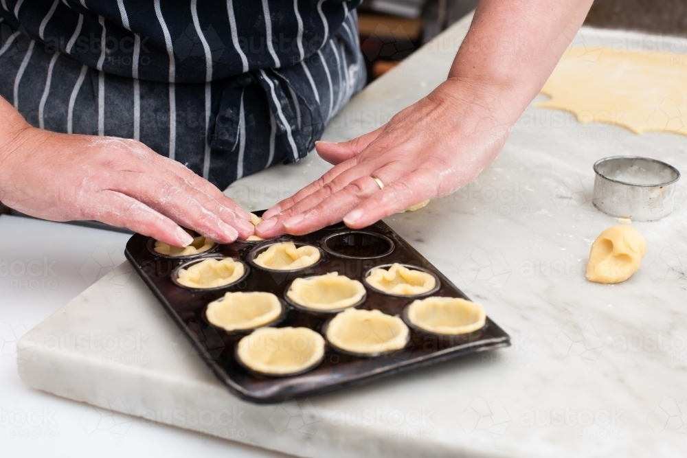 Hospitality worker working pastry into a tray - Australian Stock Image