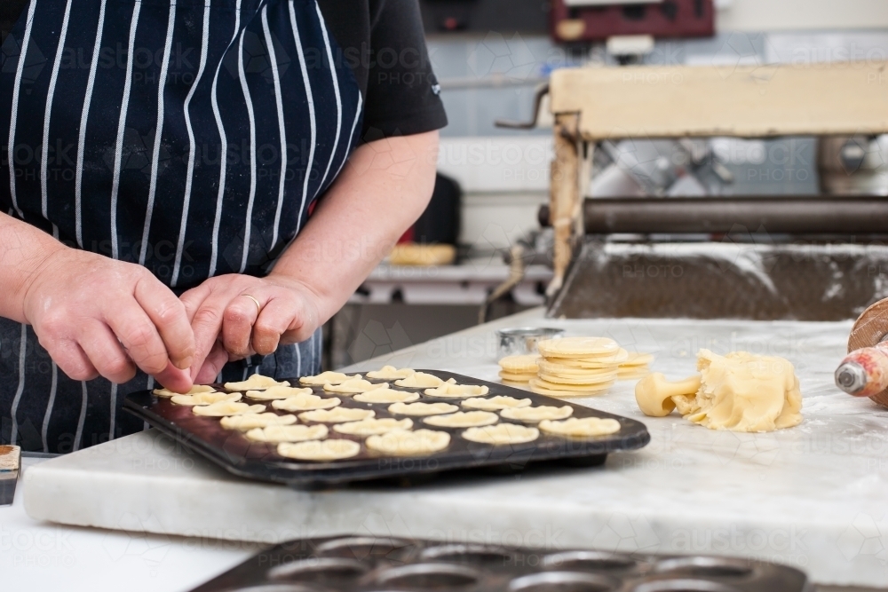 Hhospitality worker working pastry into a tray - Australian Stock Image