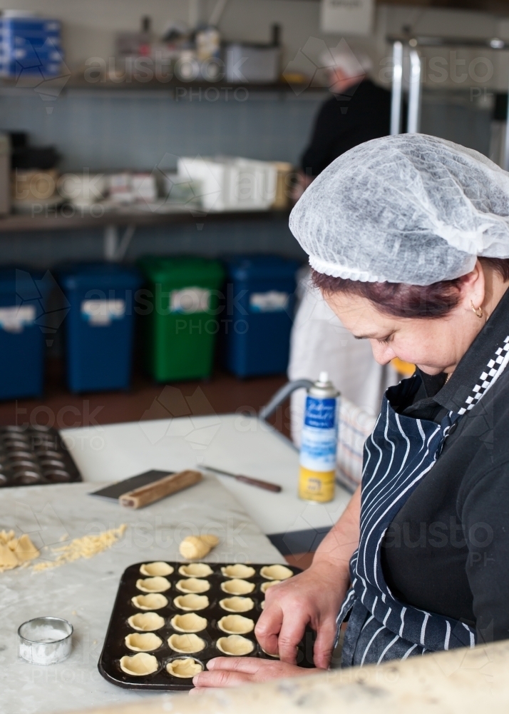 hospitality worker working pastry into a tray - Australian Stock Image