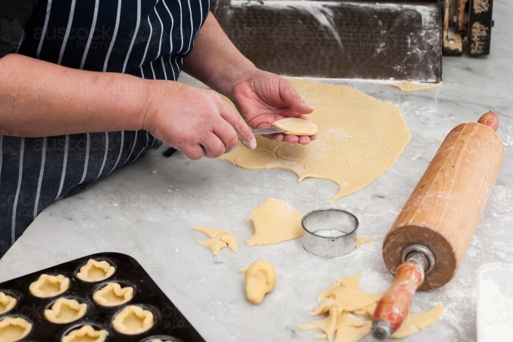 Hospitality working cutting pastry in a commercial kitchen - Australian Stock Image