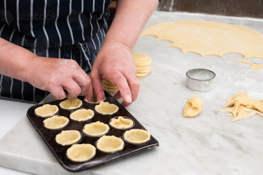 Hospitality working making pastry into a tray - Australian Stock Image