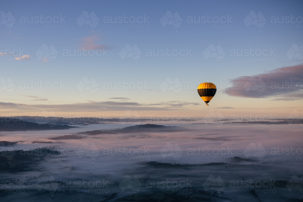 hot air balloon above the clouds early in the morning - Australian Stock Image