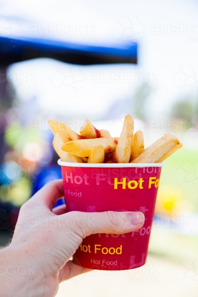 Hot Chips with tomato sauce in cup outside at event - Australian Stock Image