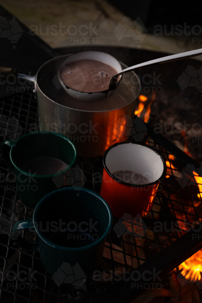 Hot chocolate drink scooped from the pot to the mugs. - Australian Stock Image