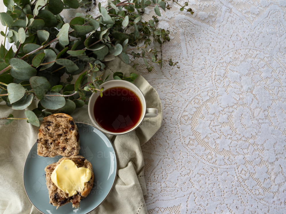 Hot Cross Bun on a plate with a cup of tea and eucalyptus branch - Australian Stock Image