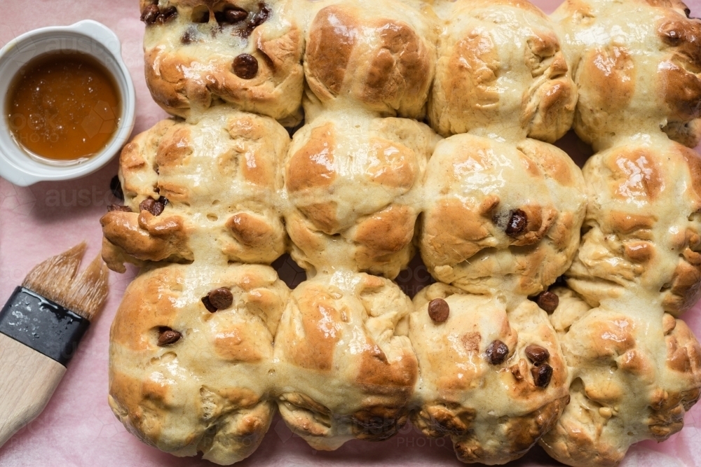 hot cross buns for Easter, glaze the warm buns with a sugar syrup - Australian Stock Image