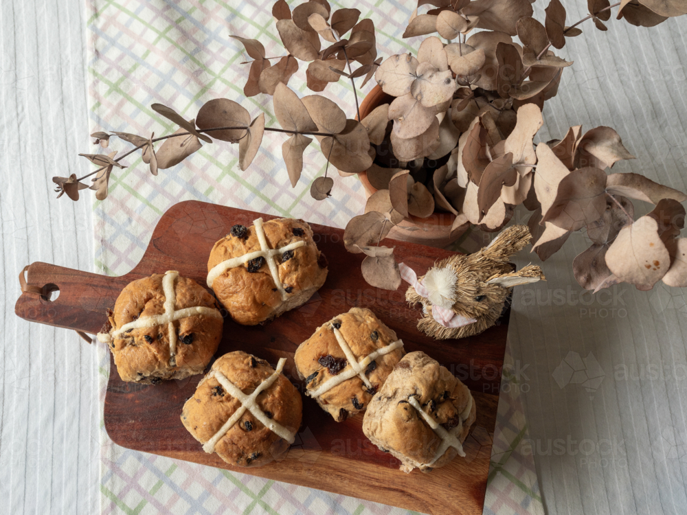 Hot cross buns on wooden serving tray with dried eucalyptus and rabbit decoration on table top - Australian Stock Image