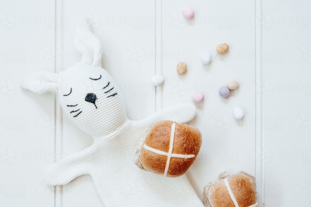 Hot cross buns with mini easter eggs and bunny rabbit puppet on white background - Australian Stock Image