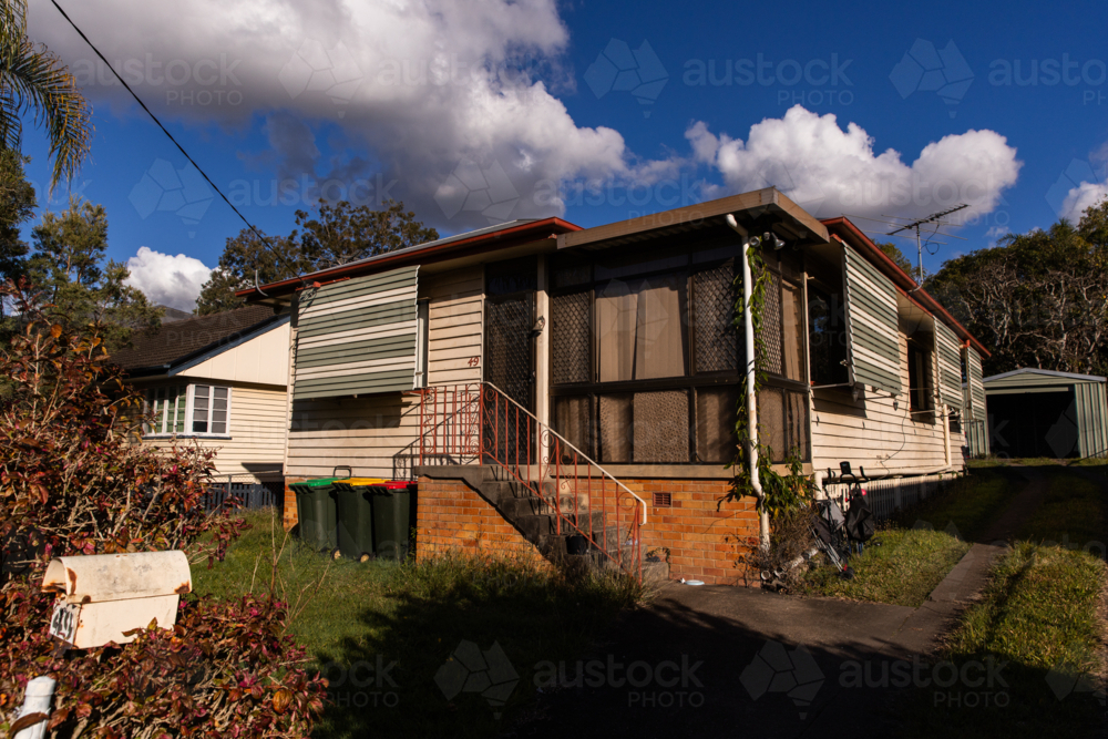 house with brown glass front windows on a sunny day - Australian Stock Image