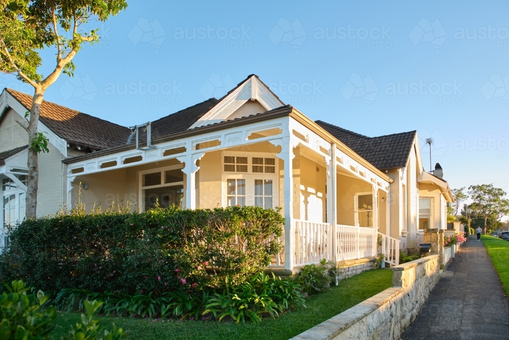 House with gabled roof, prominent eaves, and decorative timber fretwork and covered porch. - Australian Stock Image