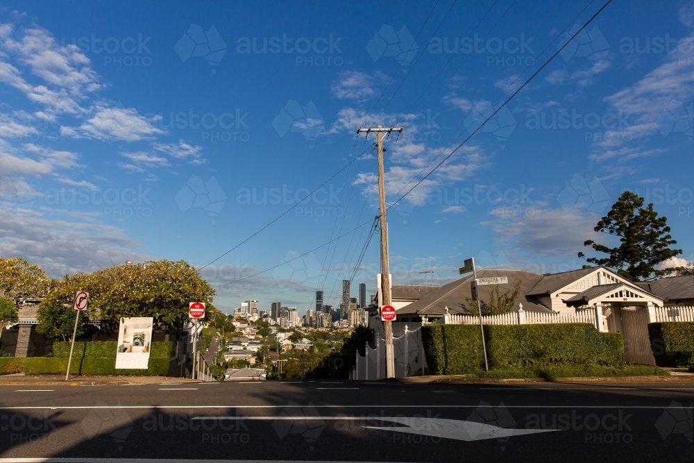 houses on the corners of a one way street in Brisbane with the city in the distance - Australian Stock Image