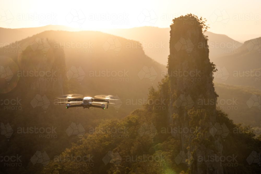 hovering drone with hazy landscape of rock pinnacle at sunset - Australian Stock Image