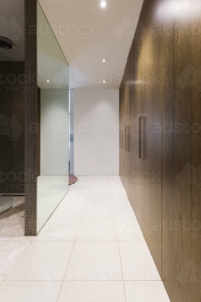 Huge walk through wardrobe with walnut doors hallway in luxurious Australian home - Australian Stock Image