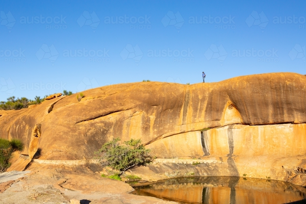 human figure atop granite rock formation in the wheatbelt - Australian Stock Image