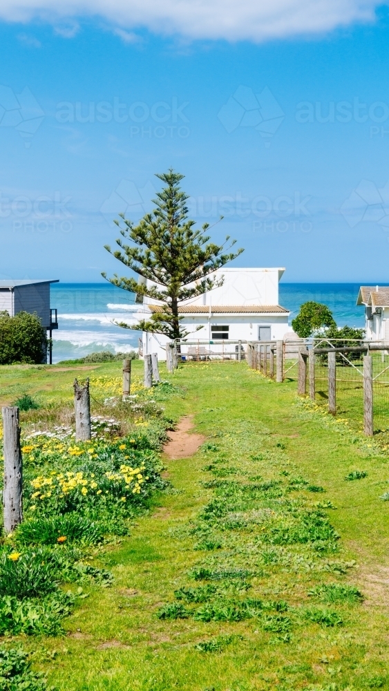 Humble beach shack by the sea, with vacant land behind - Australian Stock Image