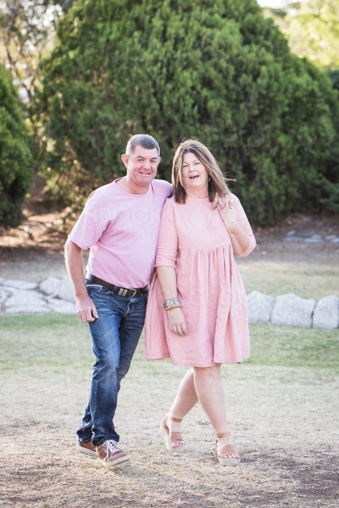 Husband and wife couple in 50s walking together laughing - Australian Stock Image