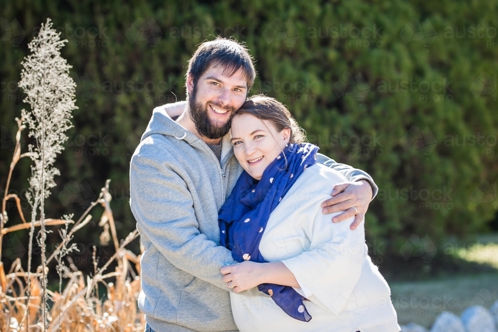 Husband and wife outside in garden cuddling close together - Australian Stock Image