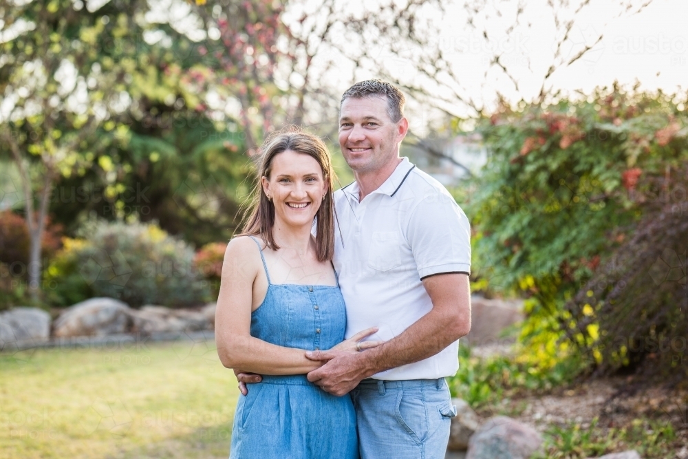 Husband and wife standing together in garden touching - Australian Stock Image