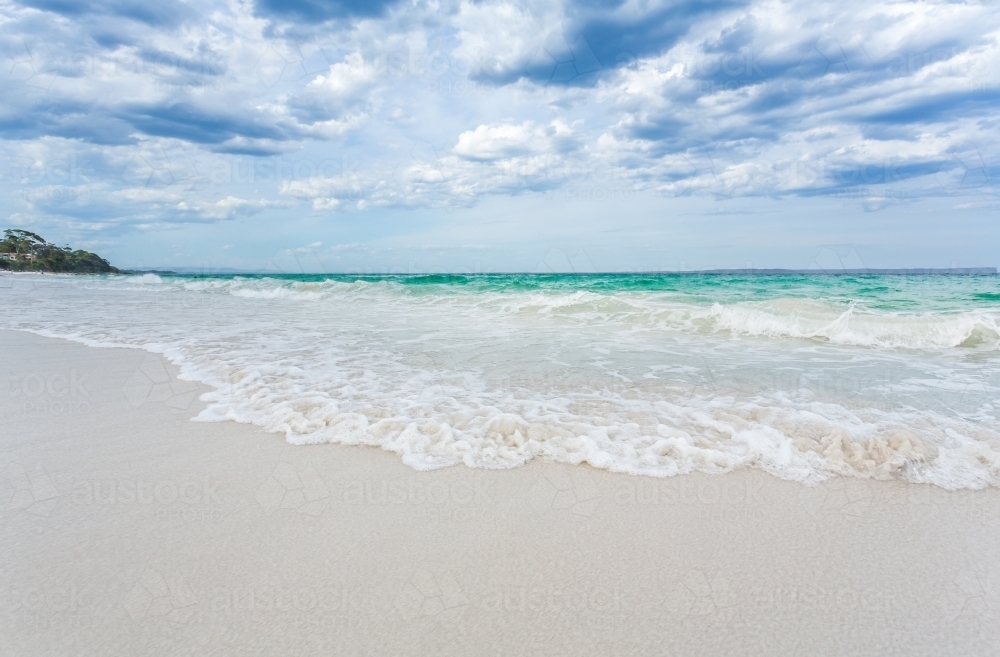 Hyams Beach waves wash ashore onto pristine white sands - Australian Stock Image