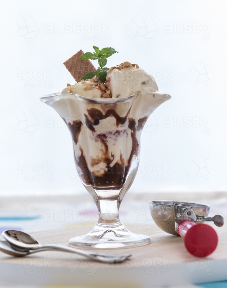 Ice cream sundae with scoop and teaspoons - Australian Stock Image