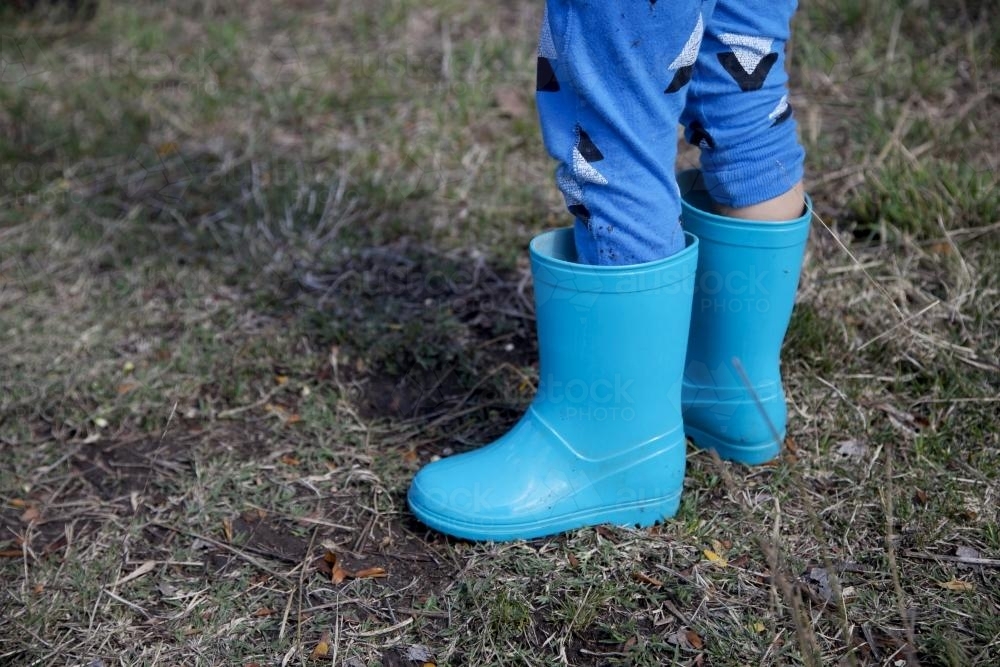 Image of a child's legs wearing light blue gumboots - Australian Stock Image