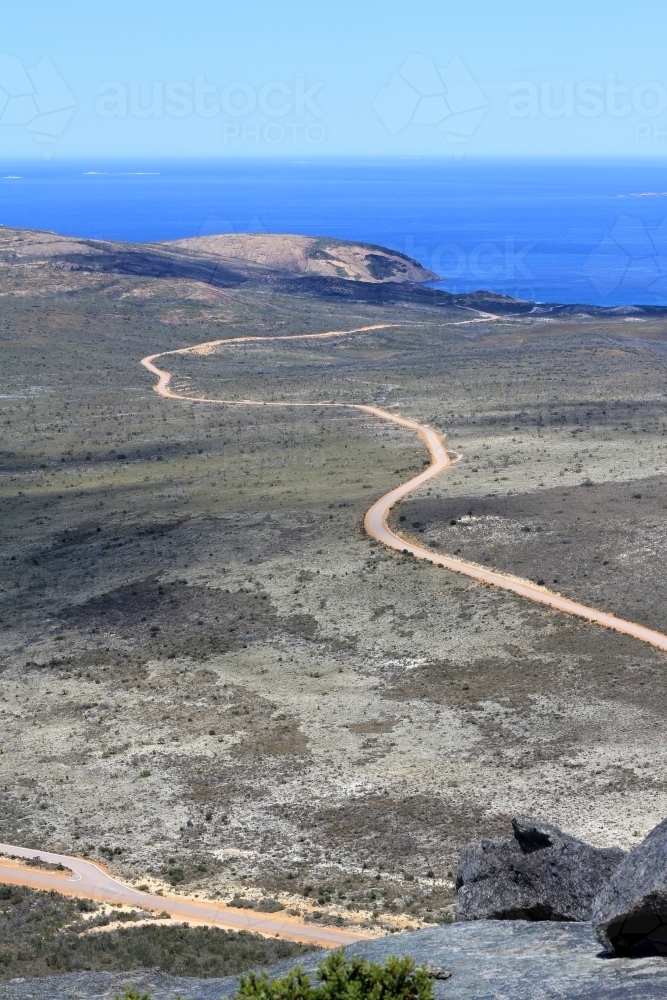 View along dirt road towards ocean from top of hill - Australian Stock Image