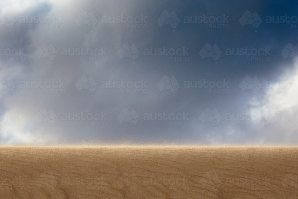 Impressive view up a sand dune towards an imposing cloudy sky - Australian Stock Image
