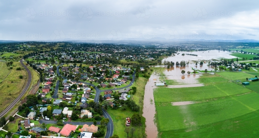 Incoming rain storm over houses in Darlington, Singleton with floodwaters cutting through paddock - Australian Stock Image
