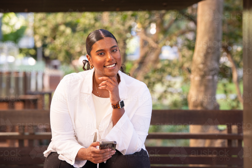 indian australian woman using phone in an outdoor setting - Australian Stock Image