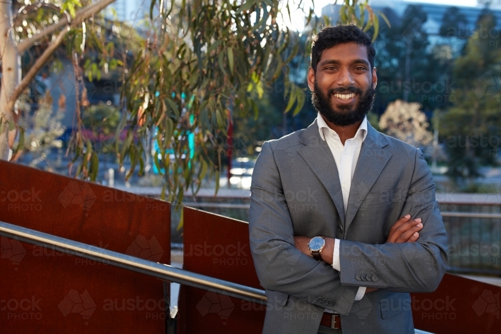 Indian businessman with open collar cheerful outdoors in city - Australian Stock Image
