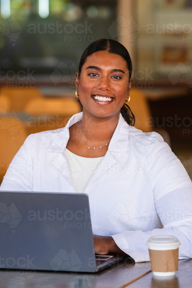 indian woman working on a laptop in a cafe - Australian Stock Image