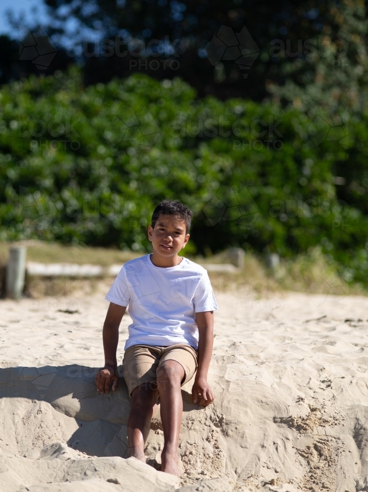Indigenous boy playing on a sand ledge - Australian Stock Image