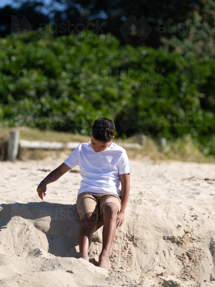 Indigenous boy playing on a sand ledge - Australian Stock Image