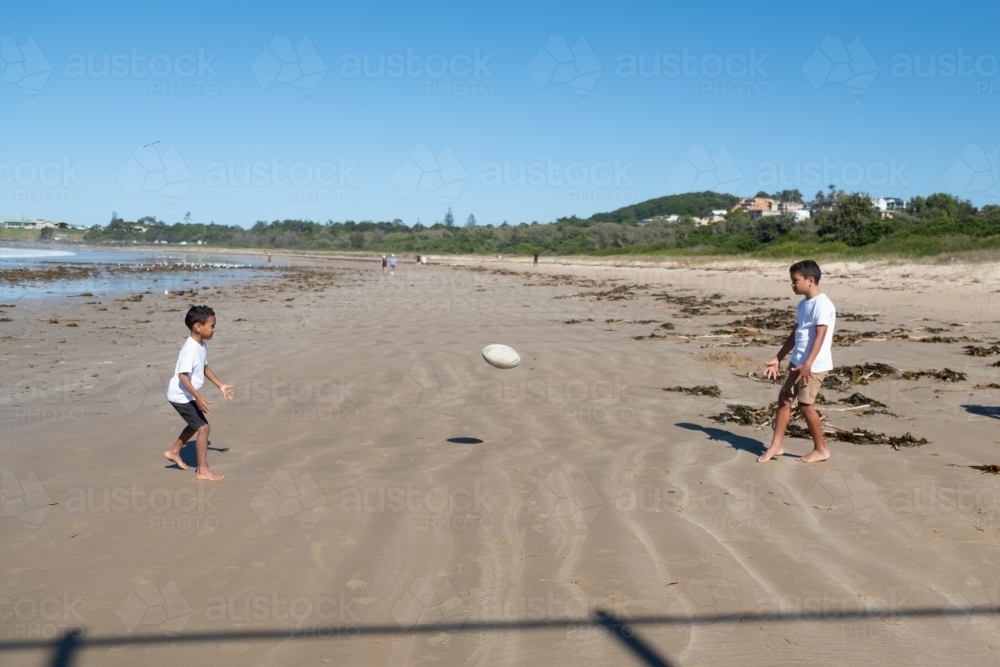 Indigenous children playing ball on the beach - Australian Stock Image