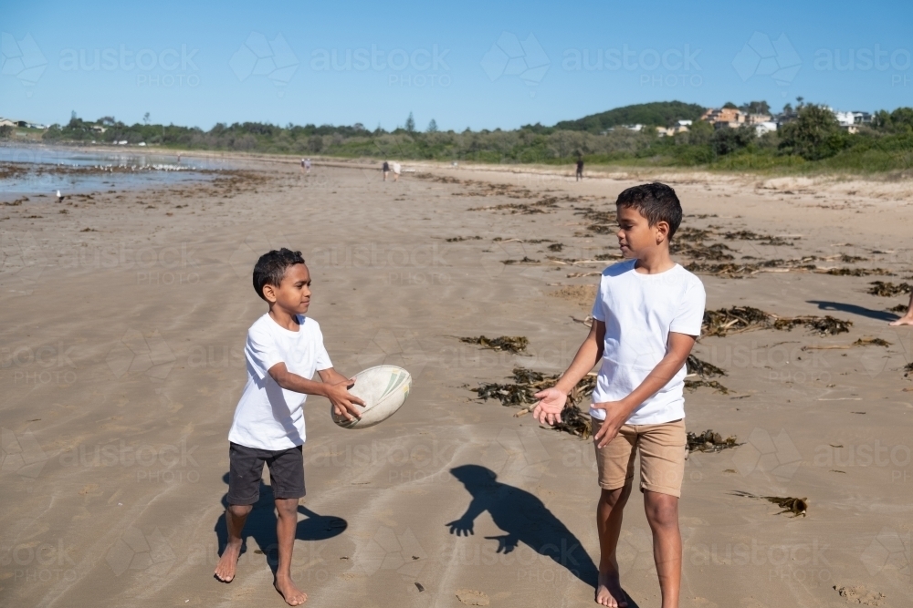 Indigenous children playing ball on the beach - Australian Stock Image